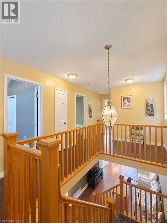 Open upper-level landing featuring wood-finish railings, wood-finish flooring, and a decorative hexagonal pendant light fixture - 52 Isabella Street, Kitchener, ON
