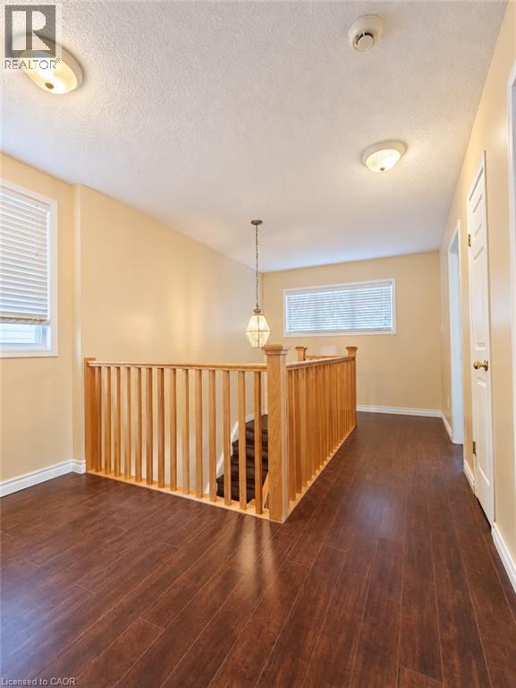 Wood-finish flooring, wood balustrade railing, dual flush-mount ceiling lights, decorative pendant light fixture, and horizontal window blinds - 52 Isabella Street, Kitchener, ON
