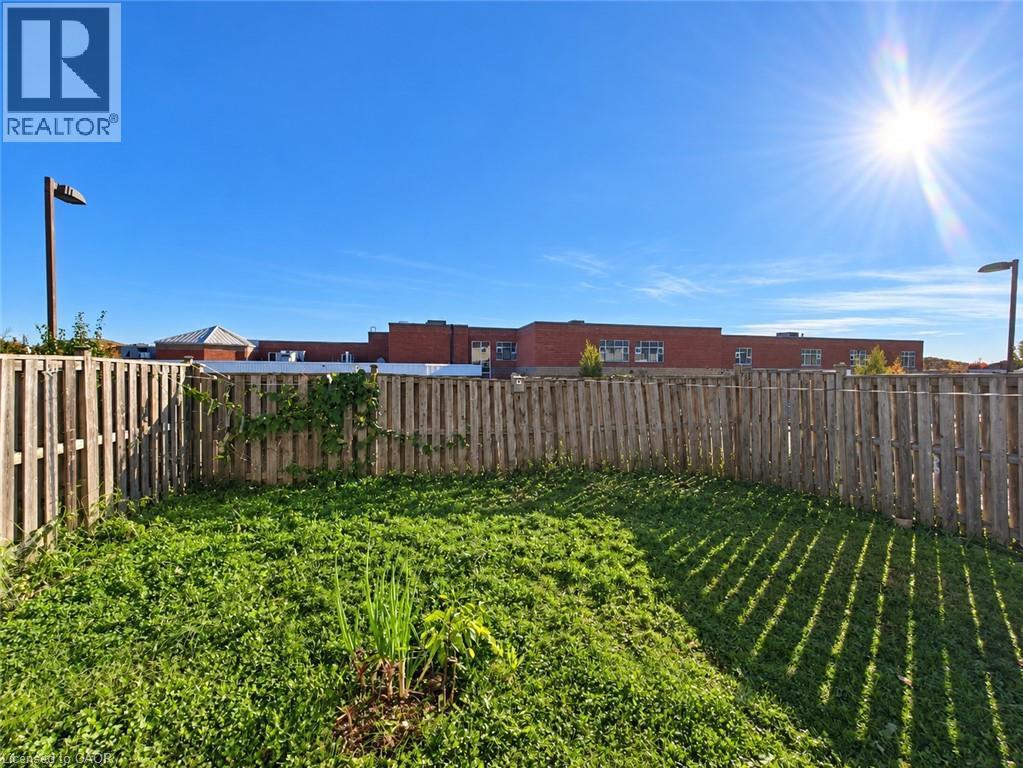 Fenced backyard featuring a grass lawn and two metal light poles - 52 Isabella Street, Kitchener, ON