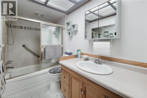 Main-floor four-piece bathroom with tub and shower combination and vanity storage - 286 Mohawk Road W, Hamilton, ON 