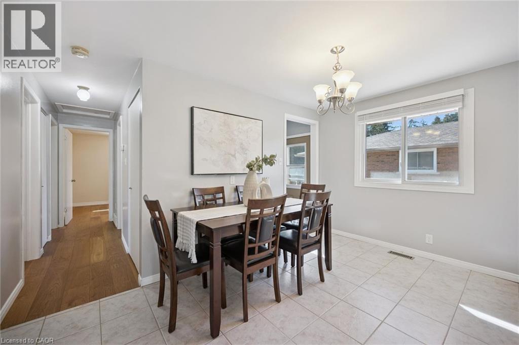Neutral-toned interior featuring ceramic tile flooring, wood-finish hallway flooring, and a multi-arm metal chandelier - 11 Caledon Court, Cambridge, ON
