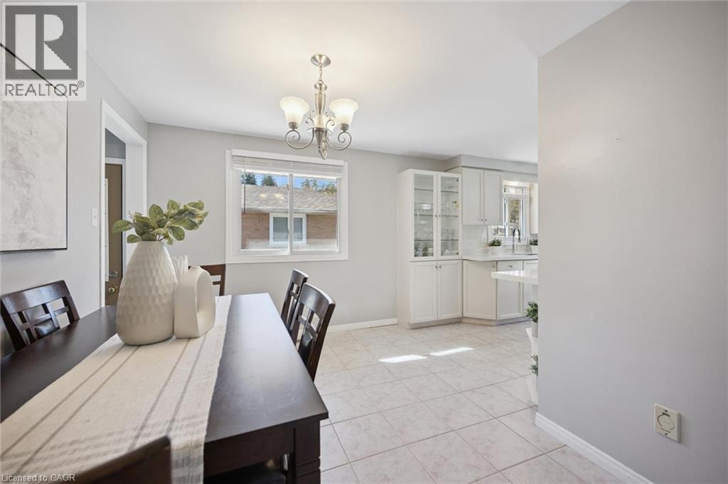 Neutral-toned room featuring ceramic tile flooring, a multi-arm chandelier, built-in display cabinetry, and a sliding window - 11 Caledon Court, Cambridge, ON