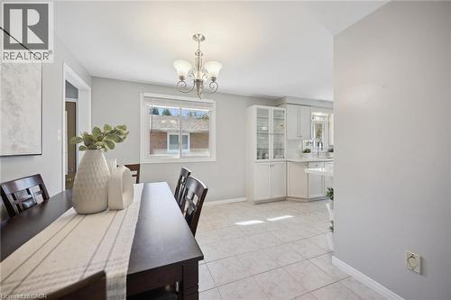 Neutral-toned room featuring ceramic tile flooring, a multi-arm chandelier, built-in display cabinetry, and a sliding window - 11 Caledon Court, Cambridge, ON 