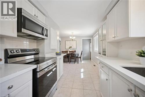 Kitchen featuring white shaker-style cabinetry, solid-surface countertops, tile flooring, and stainless steel appliances - 11 Caledon Court, Cambridge, ON 