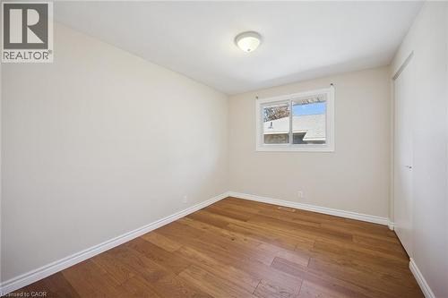 Interior room featuring wood-finish flooring, a horizontal sliding window, and a built-in closet with a white door - 11 Caledon Court, Cambridge, ON 