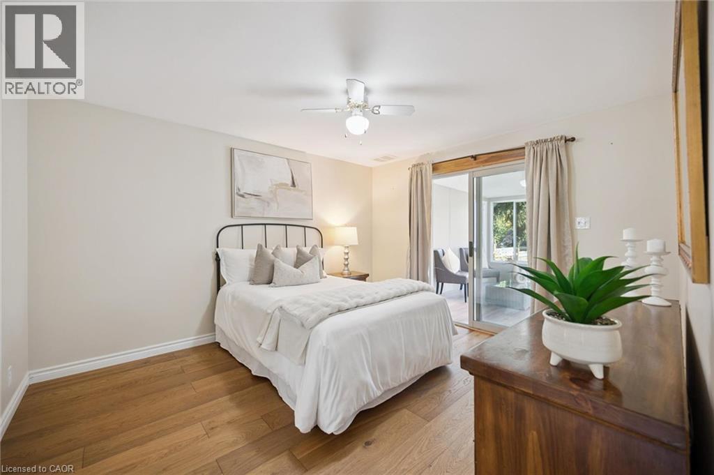 Interior room featuring wood-finish flooring, a white ceiling fan with integrated lighting, and a sliding glass door providing external access - 11 Caledon Court, Cambridge, ON