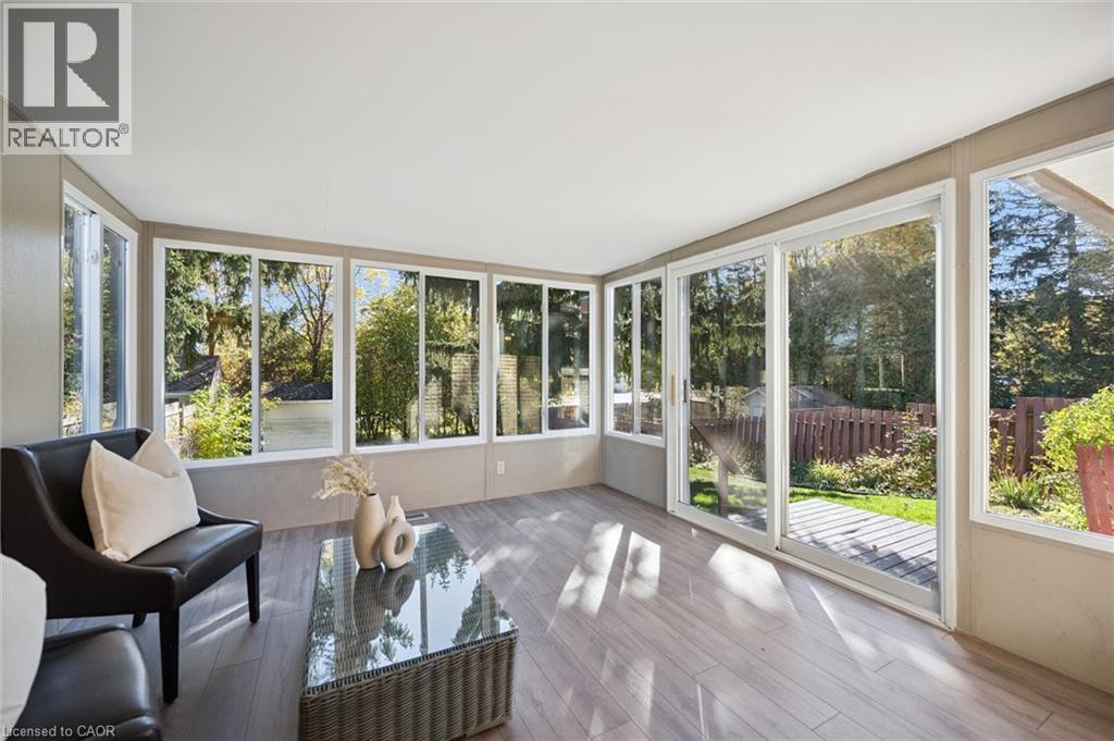 Sunroom featuring extensive floor-to-ceiling windows, sliding glass door, and wood-finish flooring - 11 Caledon Court, Cambridge, ON