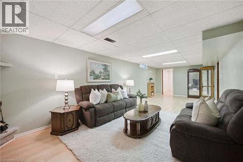 Interior space featuring light wood-finish flooring, recessed fluorescent lighting, a drop ceiling, and a fireplace hearth - 11 Caledon Court, Cambridge, ON 