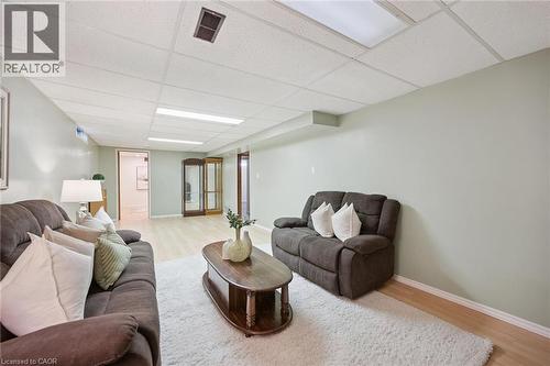 Finished interior space featuring wood-finish flooring, drop ceiling panels, and recessed fluorescent lighting - 11 Caledon Court, Cambridge, ON 