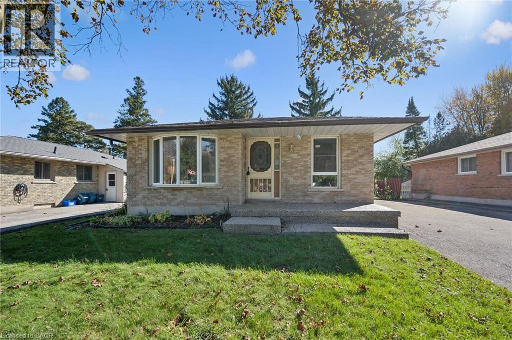 Exterior featuring a neutral-toned brick facade, a front-facing bay window, an inset entryway with decorative glass door, and a concrete porch with an overhanging roofline - 11 Caledon Court, Cambridge, ON