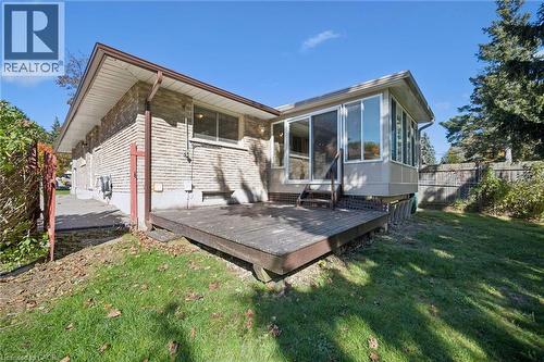 Brick exterior featuring an elevated wood deck, multi-pane window sunroom, sliding glass patio door, and expansive lawn - 11 Caledon Court, Cambridge, ON 