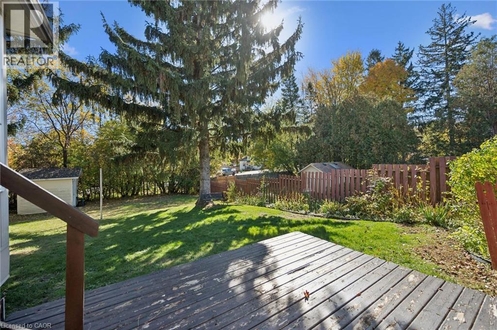Backyard featuring a wood deck, manicured lawn, perimeter fencing, and mature trees - 11 Caledon Court, Cambridge, ON