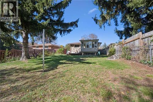 Expansive backyard featuring a level lawn, mature evergreen trees, and wood perimeter fencing - 11 Caledon Court, Cambridge, ON 