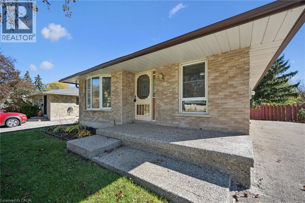 Exterior facade featuring light-toned brick masonry, an overhanging roofline, exposed aggregate concrete steps, and a multi-pane bay window - 11 Caledon Court, Cambridge, ON