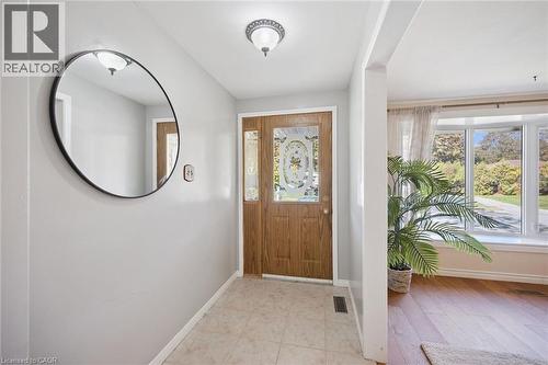 Entryway featuring a wood-grain door with decorative glass inlay, neutral floor tile, semi-flush mount ceiling lighting, and a bay window - 11 Caledon Court, Cambridge, ON 