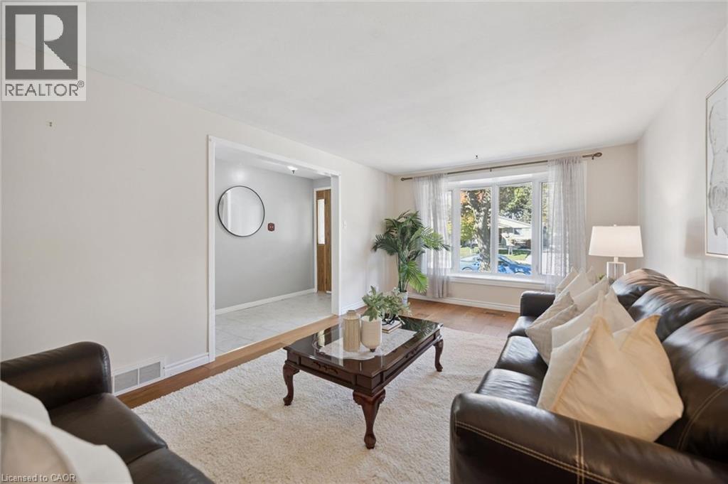 Living area featuring wood-finish flooring, a multi-paneled bay window, and neutral wall tones - 11 Caledon Court, Cambridge, ON