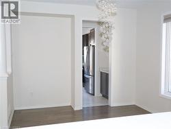 Wood-finish flooring, decorative multi-globe crystal pendant lighting, and stainless steel kitchen appliances with grey cabinetry -