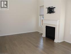 High ceilings, wood-finish flooring, and a fireplace featuring a white mantel and a black metal surround -