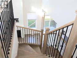 Staircase featuring wood-finish treads, square-profile newel posts, and decorative wrought iron balusters -