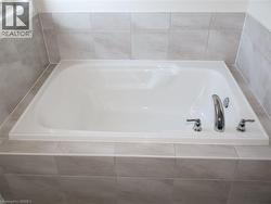 Built-in soaking tub with a polished chrome deck-mounted faucet and neutral large-format tile surround -