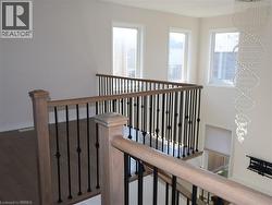 Staircase featuring wood-finish railings, black metal balusters, wood-finish flooring, and a multi-tiered decorative crystal chandelier -