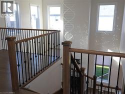 Elevated landing featuring wood-finish flooring, metal balusters with wooden handrails, high ceilings, multiple tall windows, and a decorative crystal chandelier -