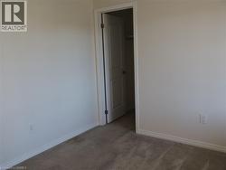 Neutral wall-to-wall carpeting, crisp off-white wall finish, and a raised-panel interior door providing access to a closet with built-in shelving -