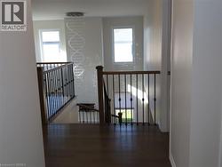 Landing featuring wood-finish flooring, metal baluster railing with wood handrails, and a multi-tiered crystal pendant light fixture -