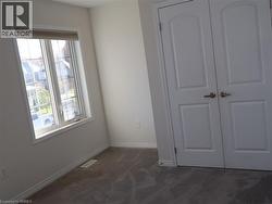 Multi-pane window with neutral wall-to-wall carpeting and double-panel doors featuring brushed nickel hardware -