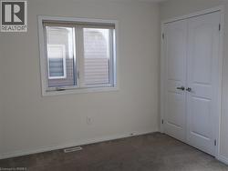 Neutral interior featuring neutral wall paint, carpeted flooring, a double-panel closet with brushed metal hardware, and a single window with white trim -