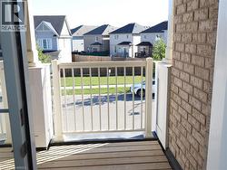 Exterior balcony featuring wood-finish decking, white aluminum railings, and beige brick siding -