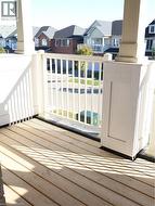 Covered balcony featuring wood-finish flooring, white square columns, and a vertical-spindle railing -