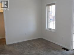 Neutral-toned interior space featuring neutral wall-to-wall carpeting, a single-hung window with a grid pattern, and an entryway to a reach-in closet -