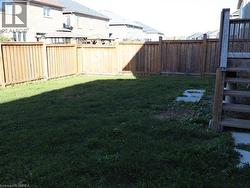 Backyard featuring a wood privacy fence, elevated wooden deck, and grass lawn -