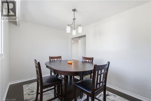Neutral interior space featuring wood-finish flooring and a three-light brushed nickel chandelier - 90 June Street, Hamilton, ON 