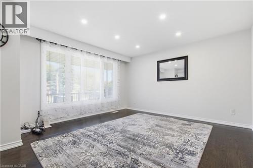 Living area featuring wood-finish flooring, recessed lighting, and a large window - 90 June Street, Hamilton, ON 