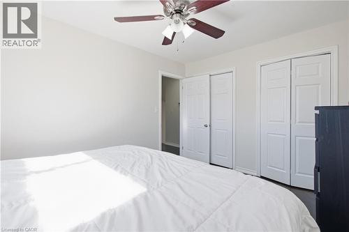 Neutral-toned interior featuring a ceiling fan with integrated lighting, dual-panel closet doors, and wood-finish flooring - 90 June Street, Hamilton, ON 