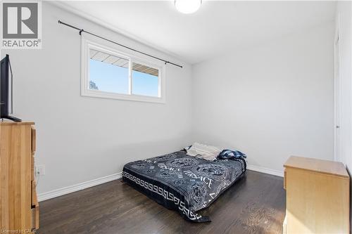 Interior room featuring dark-stained wood flooring, a single sliding window with a matte black curtain rod, and a flush-mount ceiling light fixture - 90 June Street, Hamilton, ON 