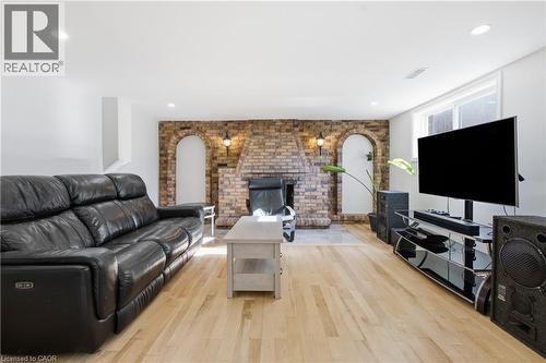 Living area featuring wood-finish flooring, recessed lighting, and a brick fireplace surround with dual arched built-in wall niches - 90 June Street, Hamilton, ON 