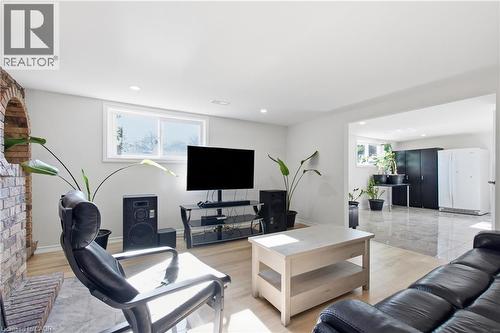 Living area featuring wood-finish flooring, a masonry fireplace with an arched hearth, and recessed lighting - 90 June Street, Hamilton, ON 
