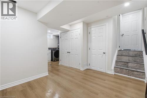 Wood-finish flooring, double-panel closet doors, recessed lighting, and stairs featuring stone-finish treads - 90 June Street, Hamilton, ON 
