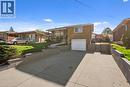 Split-level exterior featuring a brick and stone facade, integrated single-car garage, concrete driveway, and tiered retaining walls - 90 June Street, Hamilton, ON 