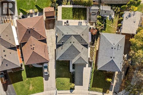 Aerial perspective featuring a multi-gabled asphalt shingle roof, a private concrete driveway, and a fenced rear lawn - 90 June Street, Hamilton, ON 