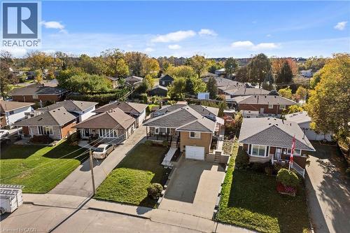 Aerial perspective featuring a detached residential property with a brick exterior, shingle roof, concrete driveway, attached single-car garage, and landscaped front lawn - 90 June Street, Hamilton, ON 