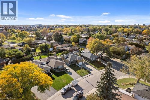 Aerial perspective of a residential setting featuring asphalt paved streets, concrete sidewalks, mature deciduous trees, and residential lots with manicured lawns - 90 June Street, Hamilton, ON 