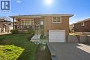 Brick exterior featuring stone accents, a covered front porch, an integrated single-car garage, and a concrete driveway - 90 June Street, Hamilton, ON 