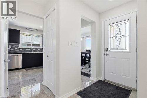 Entryway featuring a white door with a decorative leaded glass insert, stone-finish tile flooring, and closet storage with a paneled door - 90 June Street, Hamilton, ON 