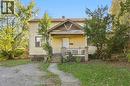 Two-story home with horizontal siding, a covered front porch featuring a gabled roofline, concrete foundation, and an gravel driveway - 14 London Street N, Hamilton, ON 
