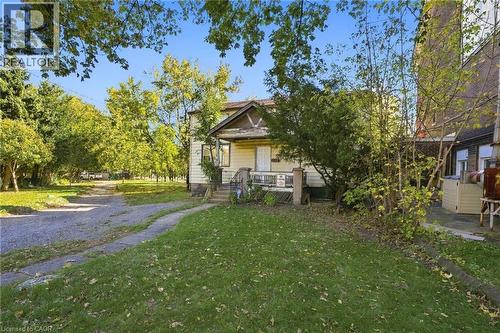 Two-story residence featuring horizontal siding, a covered front porch, an arched gable roofline, and a gravel driveway - 14 London Street N, Hamilton, ON 