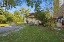 Two-story residence featuring horizontal siding, a covered front porch, an arched gable roofline, and a gravel driveway - 14 London Street N, Hamilton, ON 